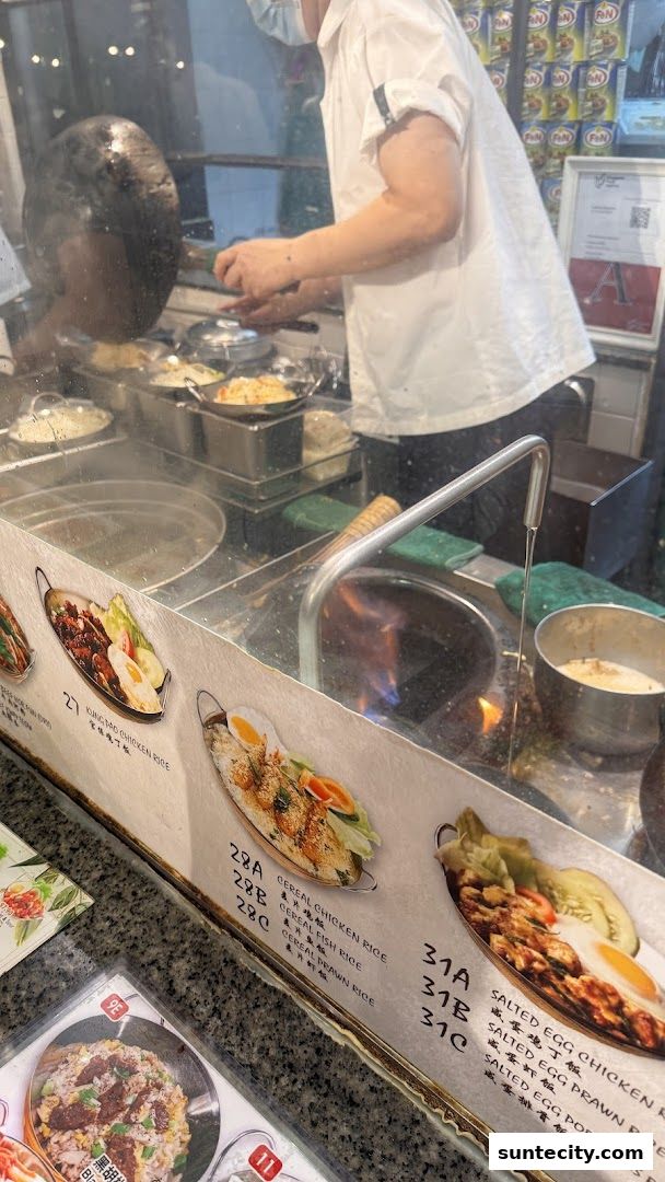 A chef cooks food in a busy kitchen with various dishes displayed.
