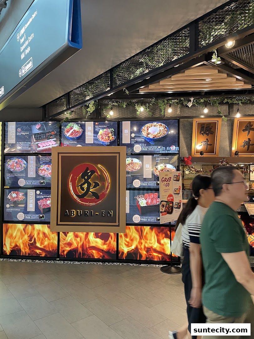 A food stall with digital menus displaying Japanese dishes and a prominent "ABURI-EN" logo.