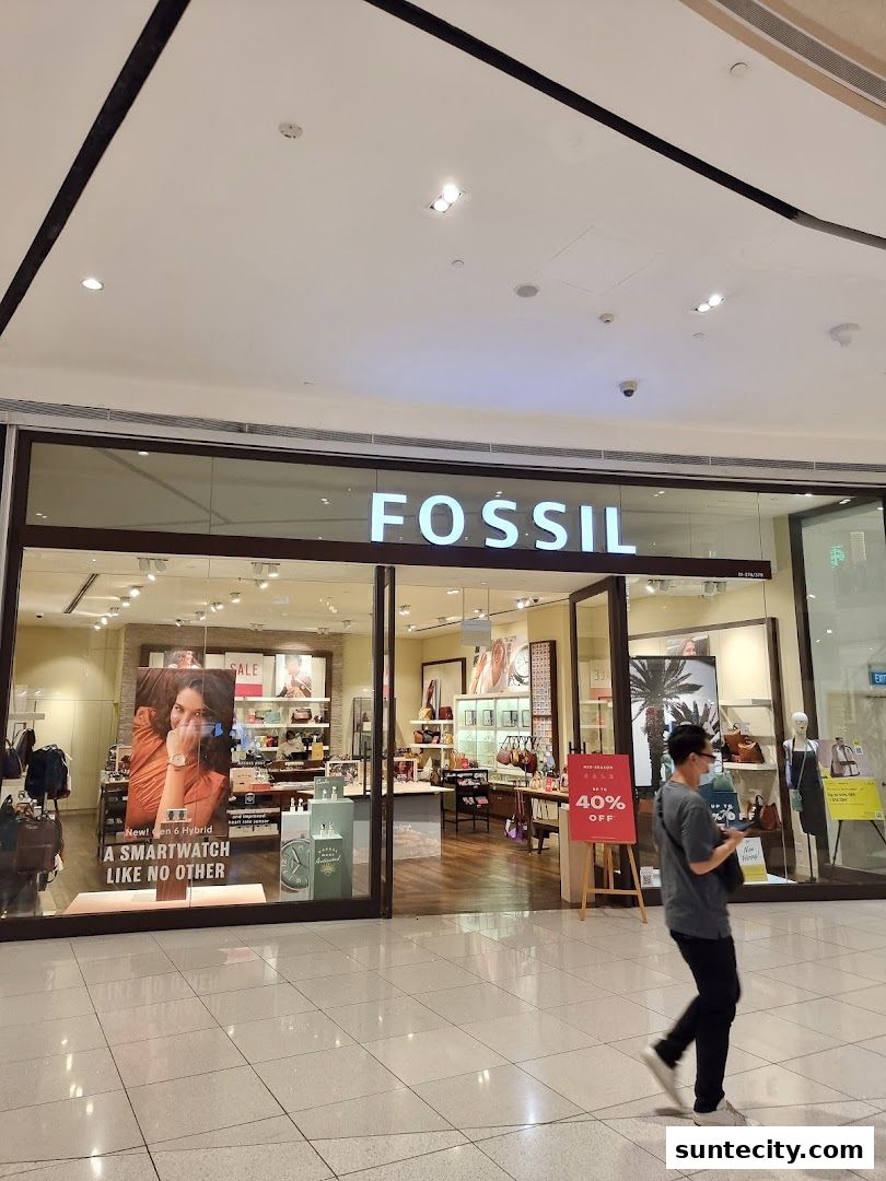 The Fossil store entrance with a sale sign and a person walking by.