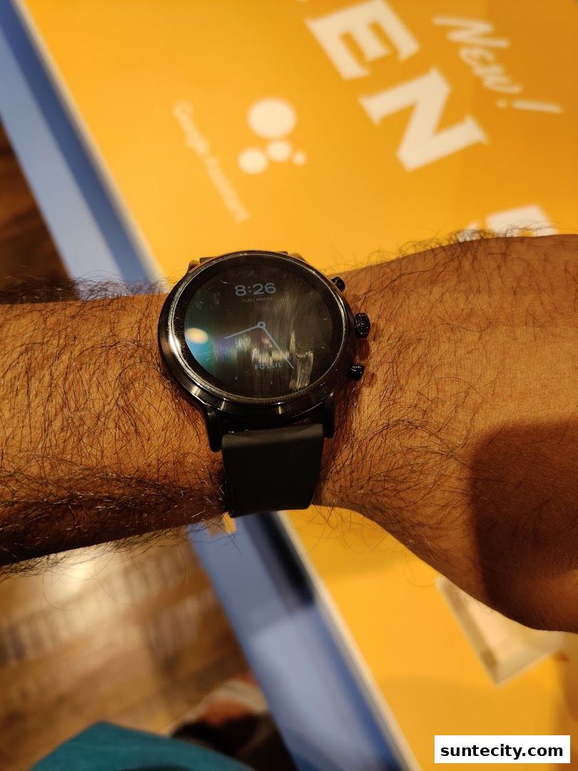 A person's wrist wearing a black Fossil smartwatch with a black strap.