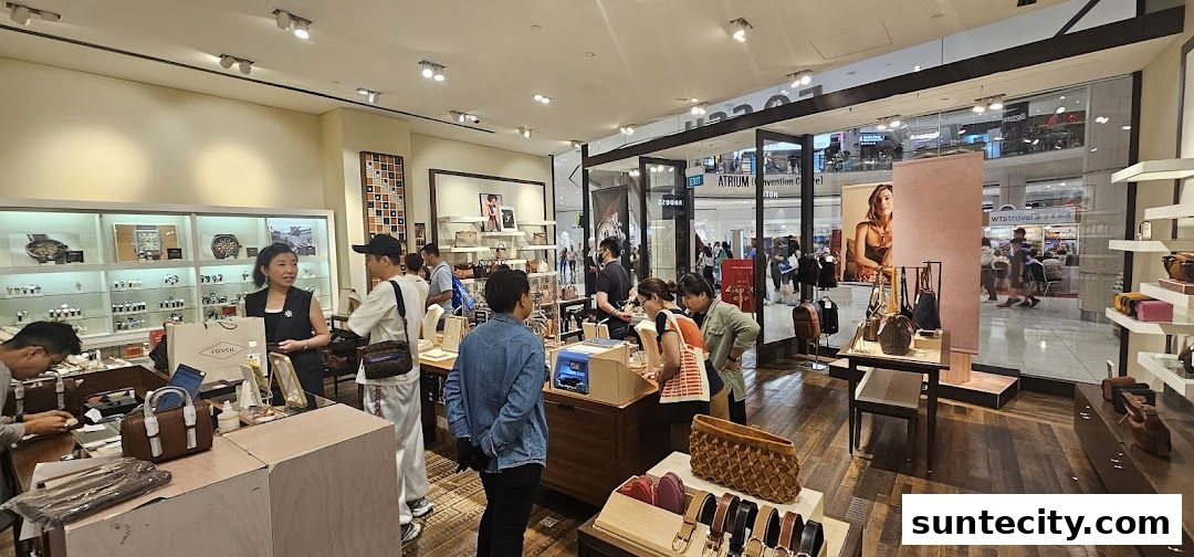 Interior view of a Fossil store showcasing watches, bags, and accessories with customers browsing.