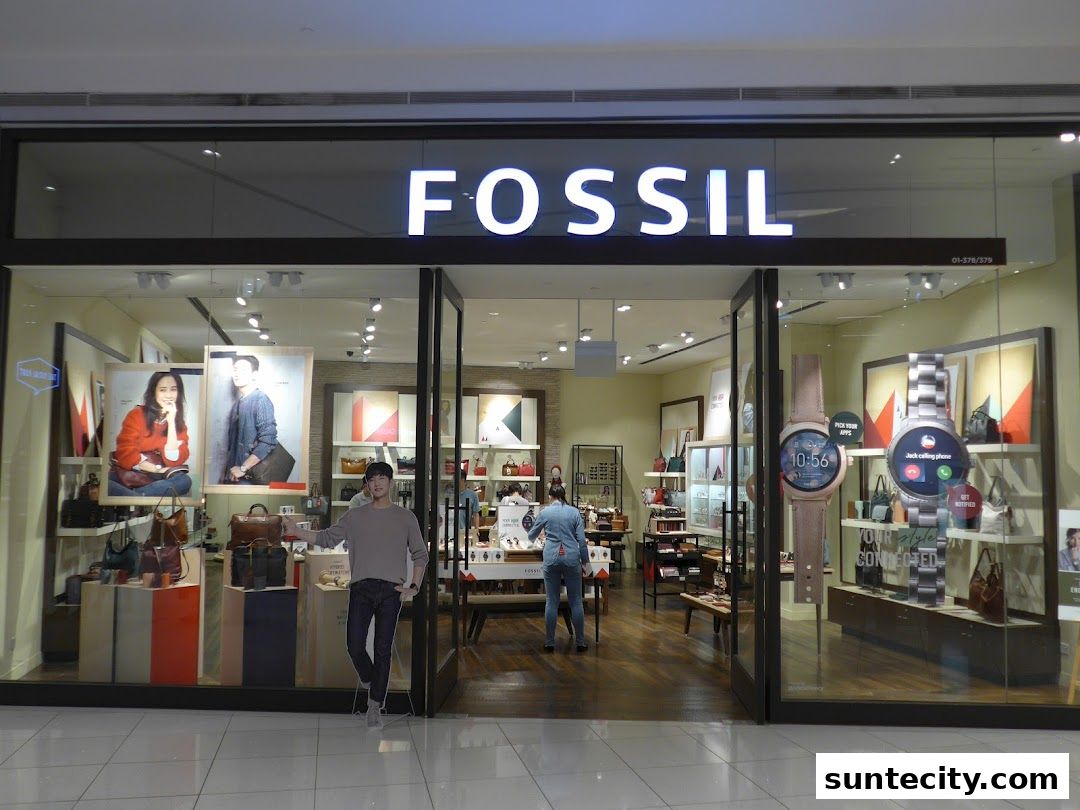 The Fossil store entrance displays fashion accessories, including watches and bags, with lifestyle imagery.