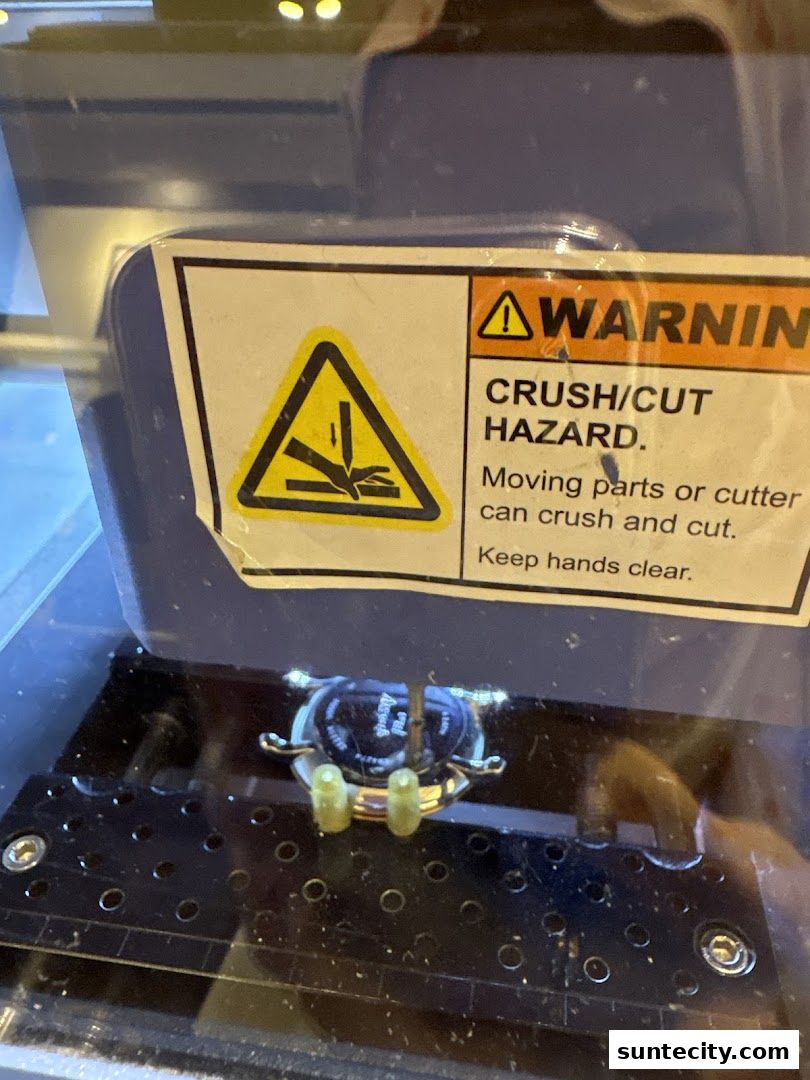 A warning label indicating a crush/cut hazard with moving parts or cutters.