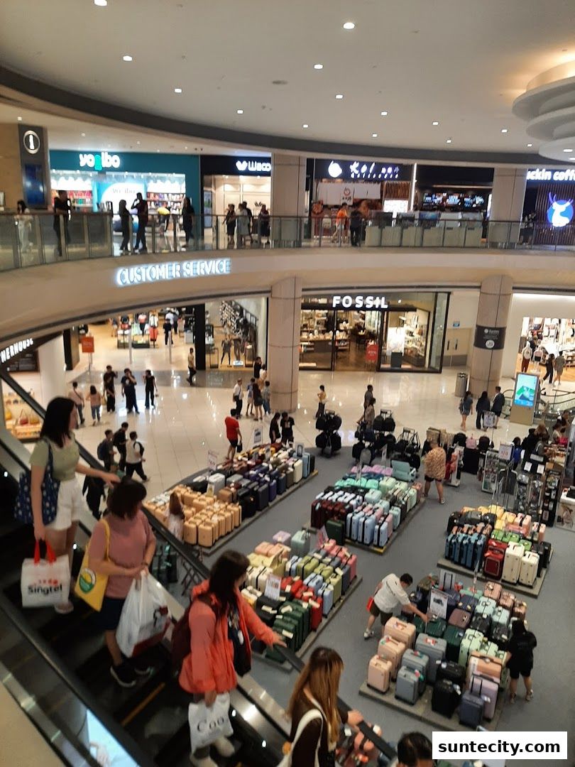 A busy shopping mall interior with escalators and various shops, including Fossil.