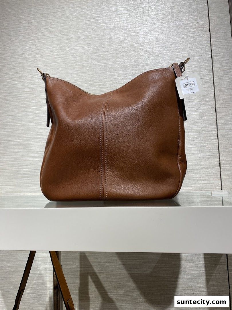 A brown leather hobo bag from Fossil is displayed on a white shelf.