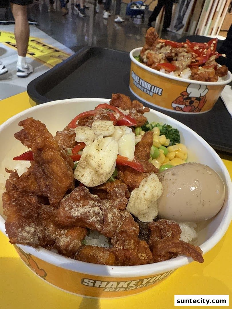 Two bowls of fried chicken with rice and vegetables, one with a boiled egg.