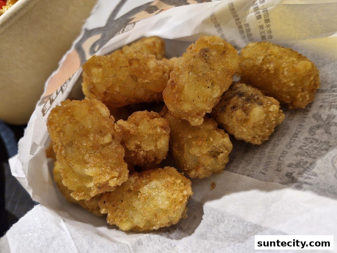 A close-up shot of crispy golden potato tots served in a paper bag.