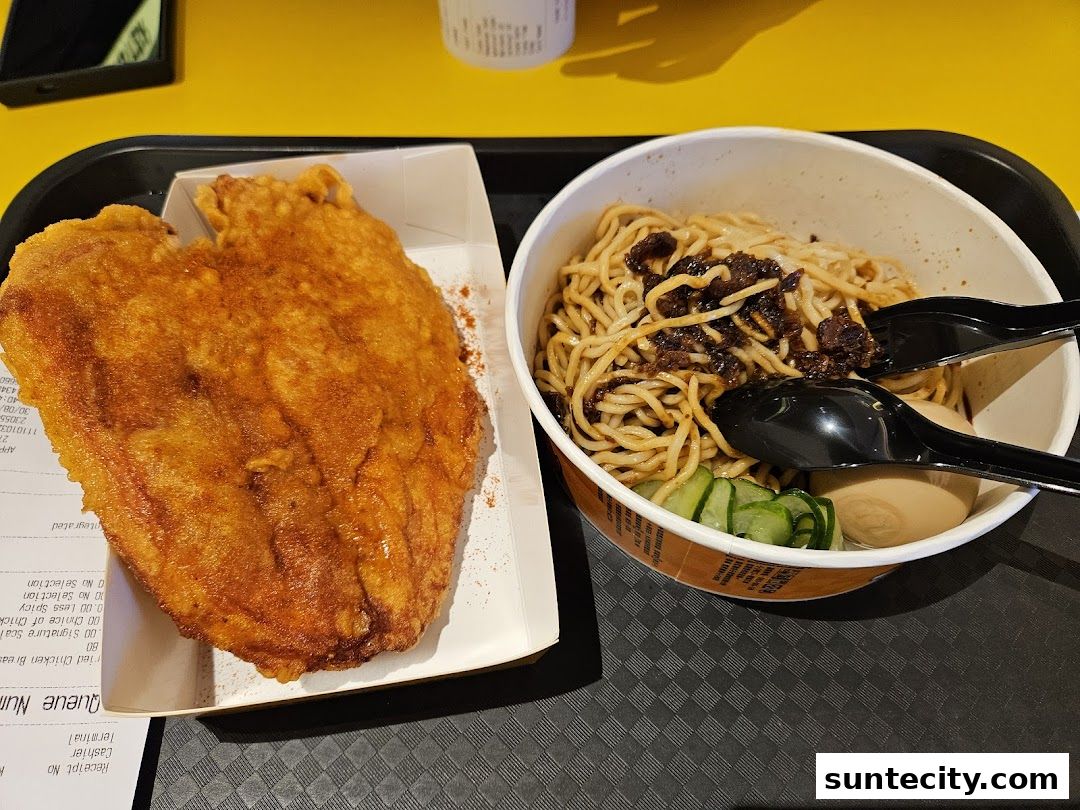 A close-up of a fried chicken cutlet and a bowl of noodles with toppings and eggs.