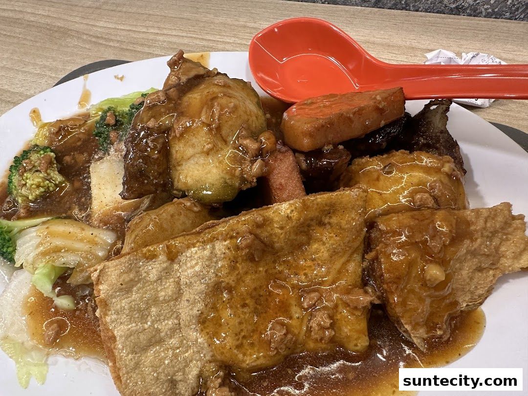 A plate of Yong Tau Foo with various ingredients in a savory sauce, served with a red spoon.