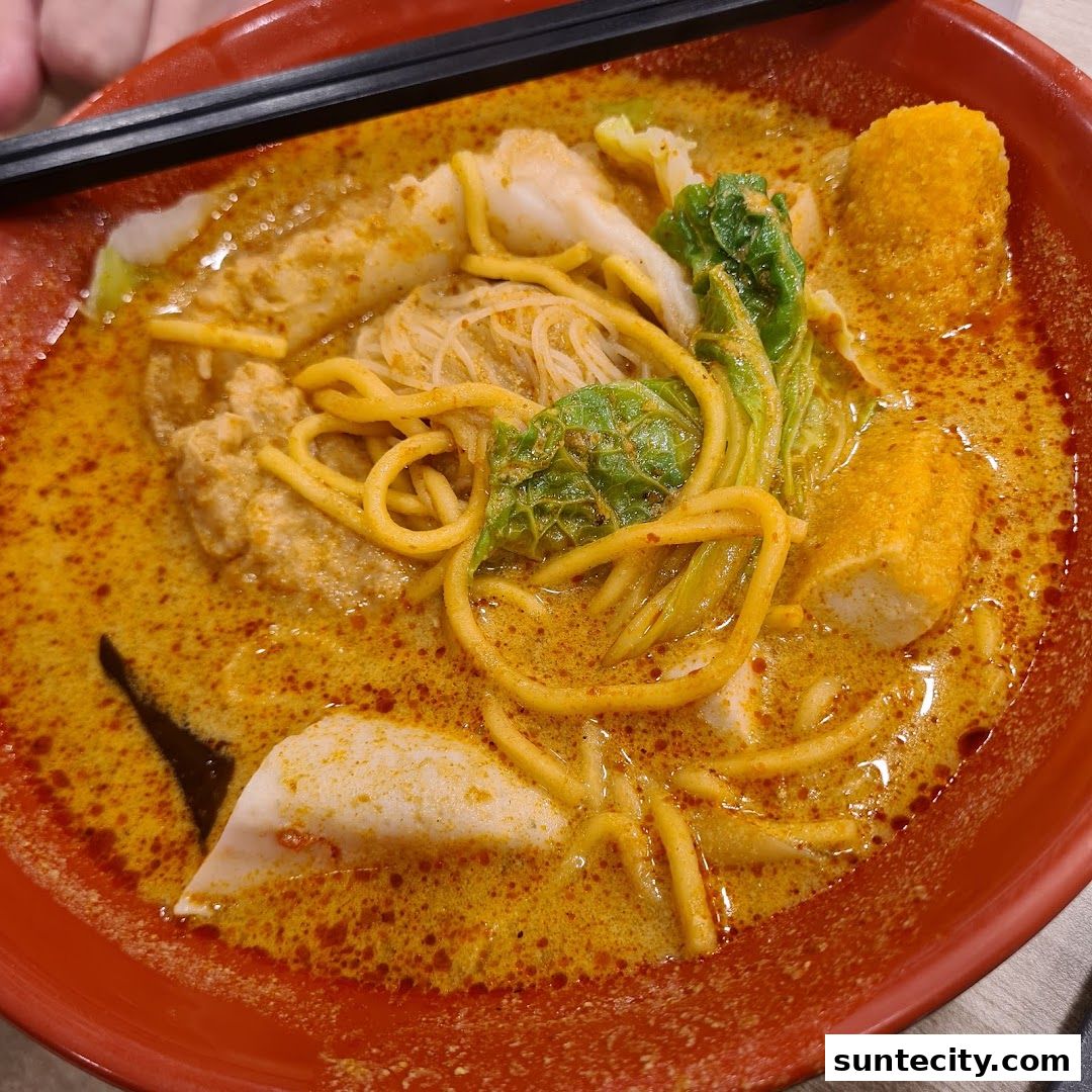 A close-up shot of a steaming bowl of Yong Tau Foo with noodles and various ingredients in a rich broth.