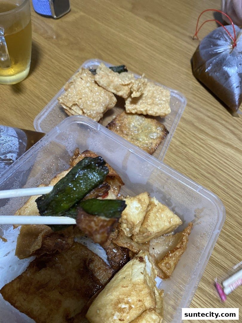 A close-up of Yong Tau Foo dishes in takeaway containers with a glass of beer.