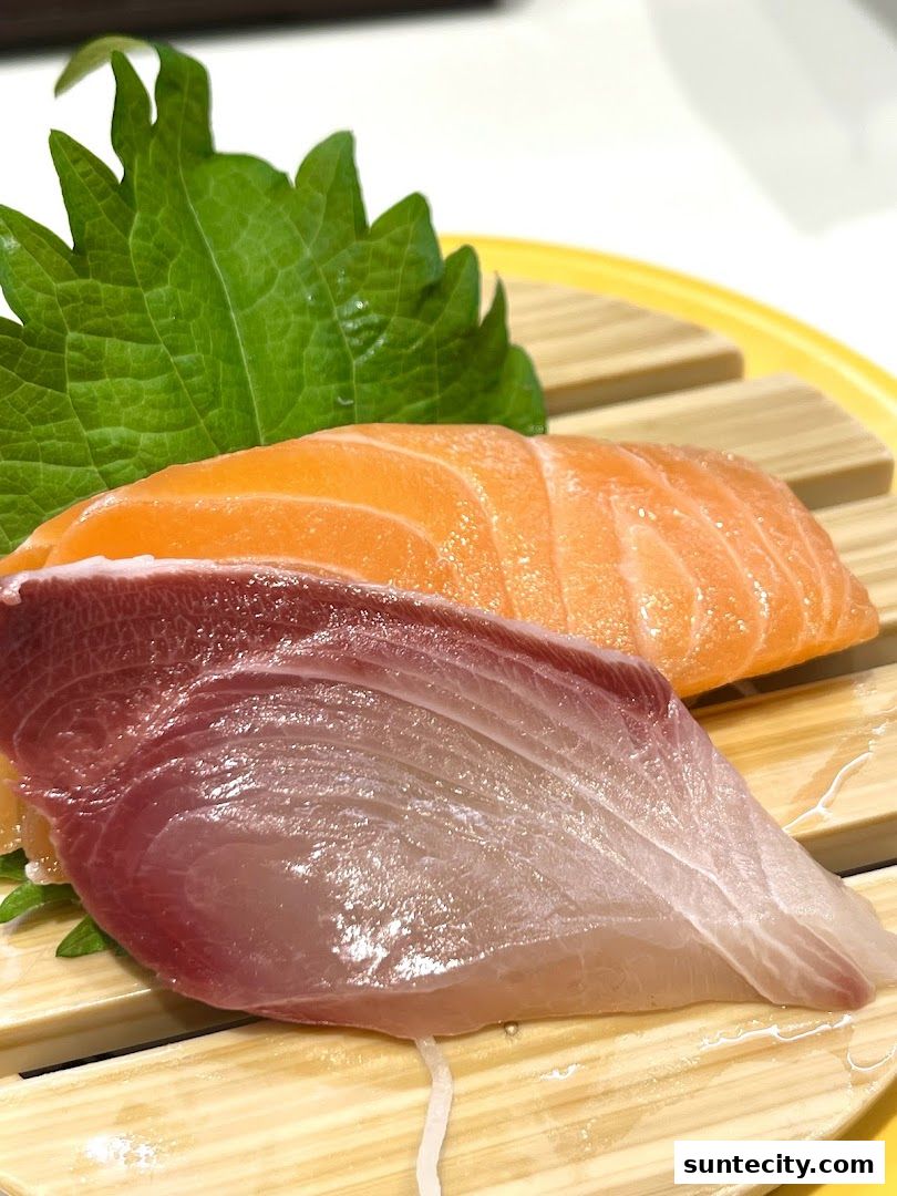 Close-up of fresh salmon and hamachi sashimi on a wooden platter with shiso leaves.
