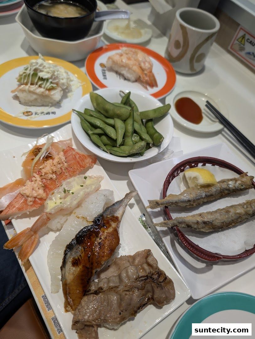 A table filled with various sushi dishes, edamame, and miso soup.
