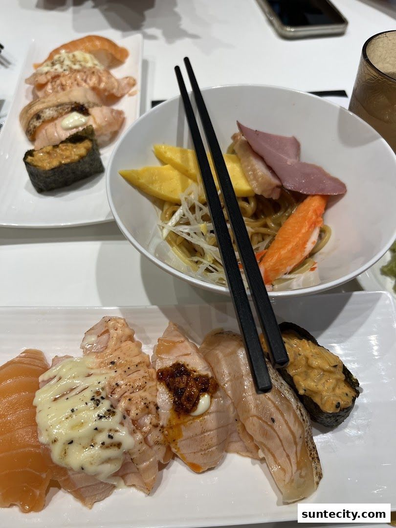 A close-up of various sushi dishes and a bowl of noodles with toppings.