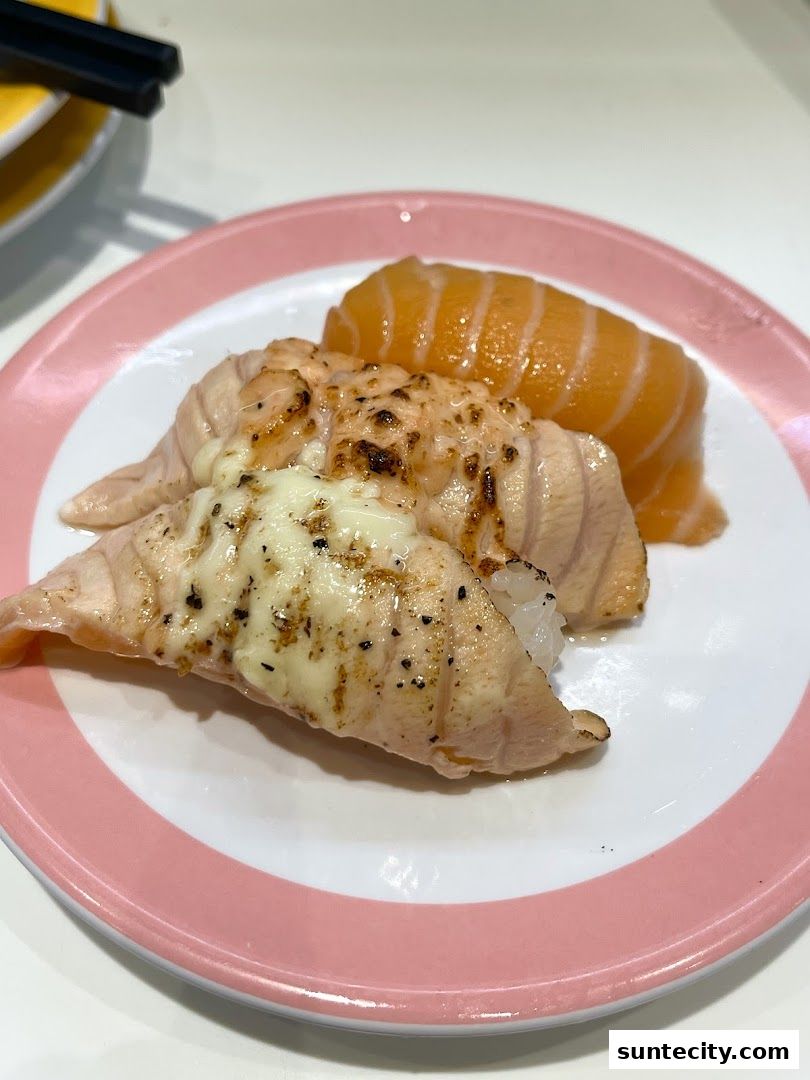 A plate of delicious salmon sushi with cheese and a plain salmon nigiri.