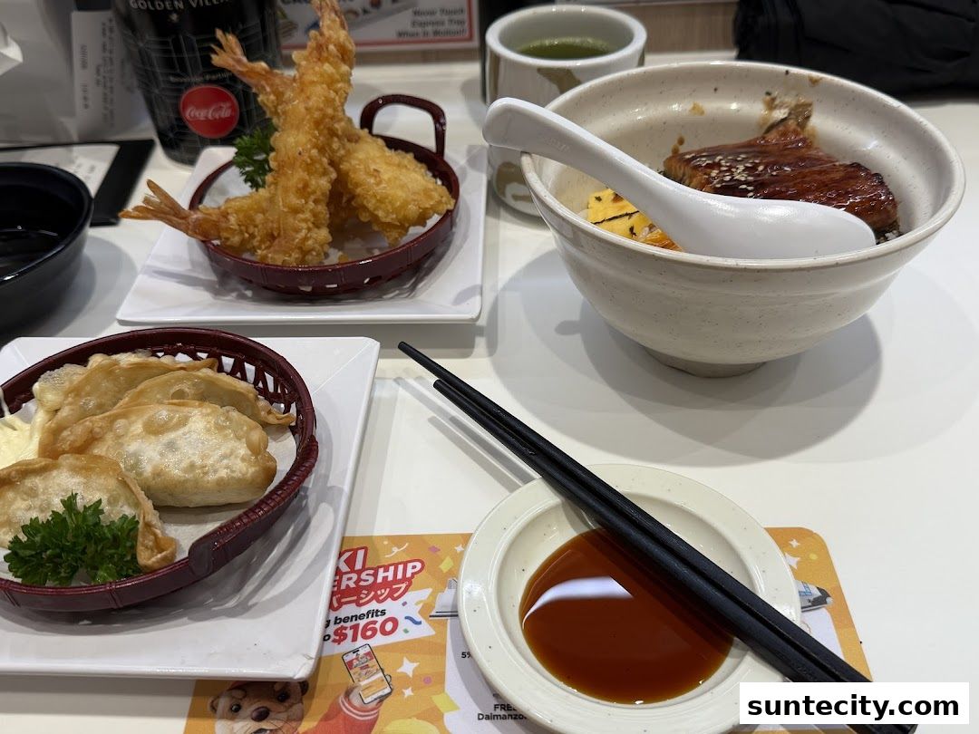A table setting with Japanese food including tempura shrimp, gyoza, and a rice bowl.