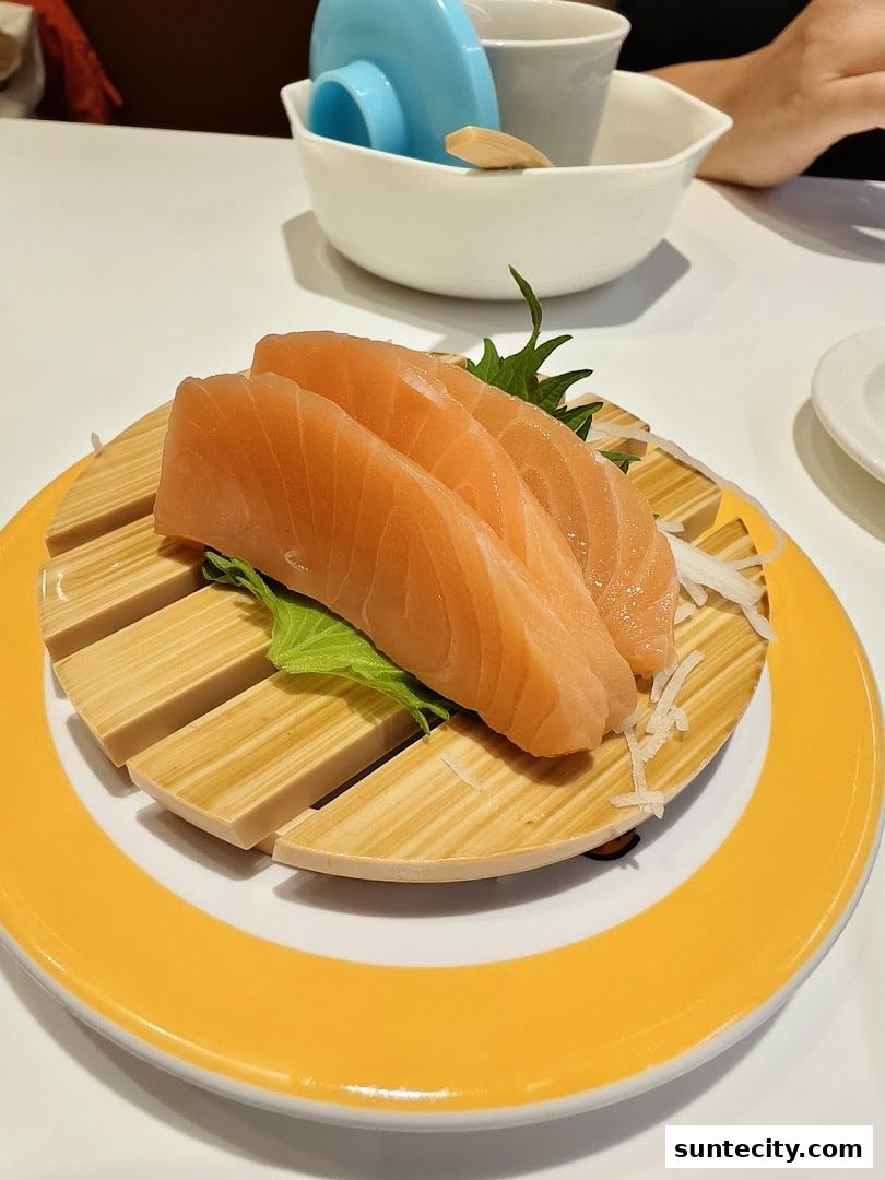 Fresh salmon sashimi served on a wooden plate with garnishes.