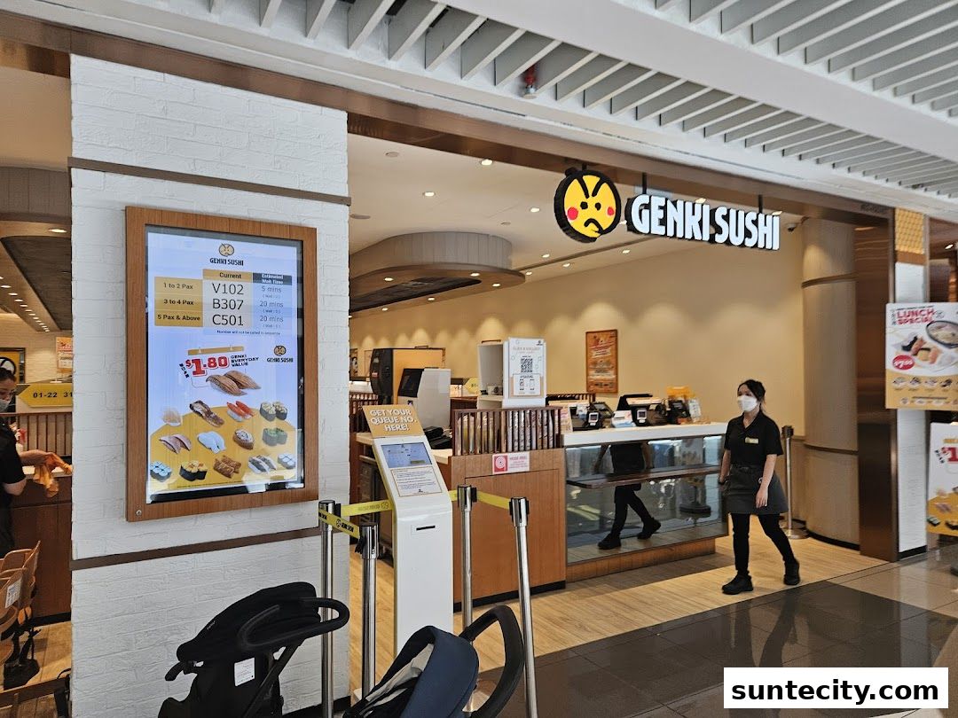 The entrance of Genki Sushi with a digital queue display and a staff member.