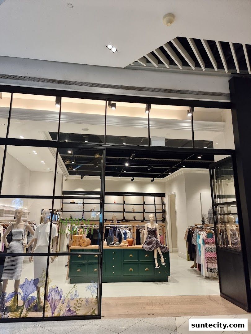 A stylish clothing store with mannequins displaying outfits and racks of apparel.