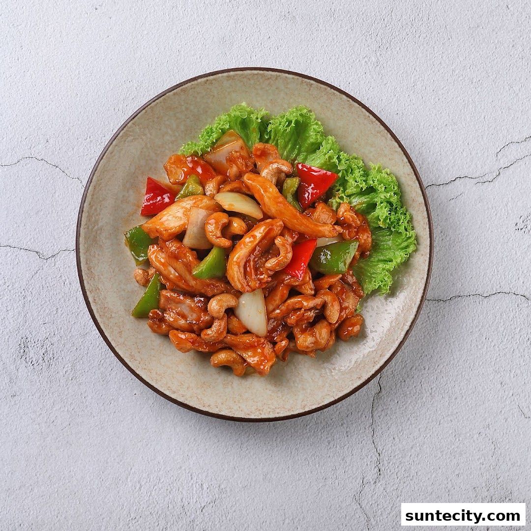 A plate of chicken with cashews, bell peppers, and onions, garnished with lettuce.