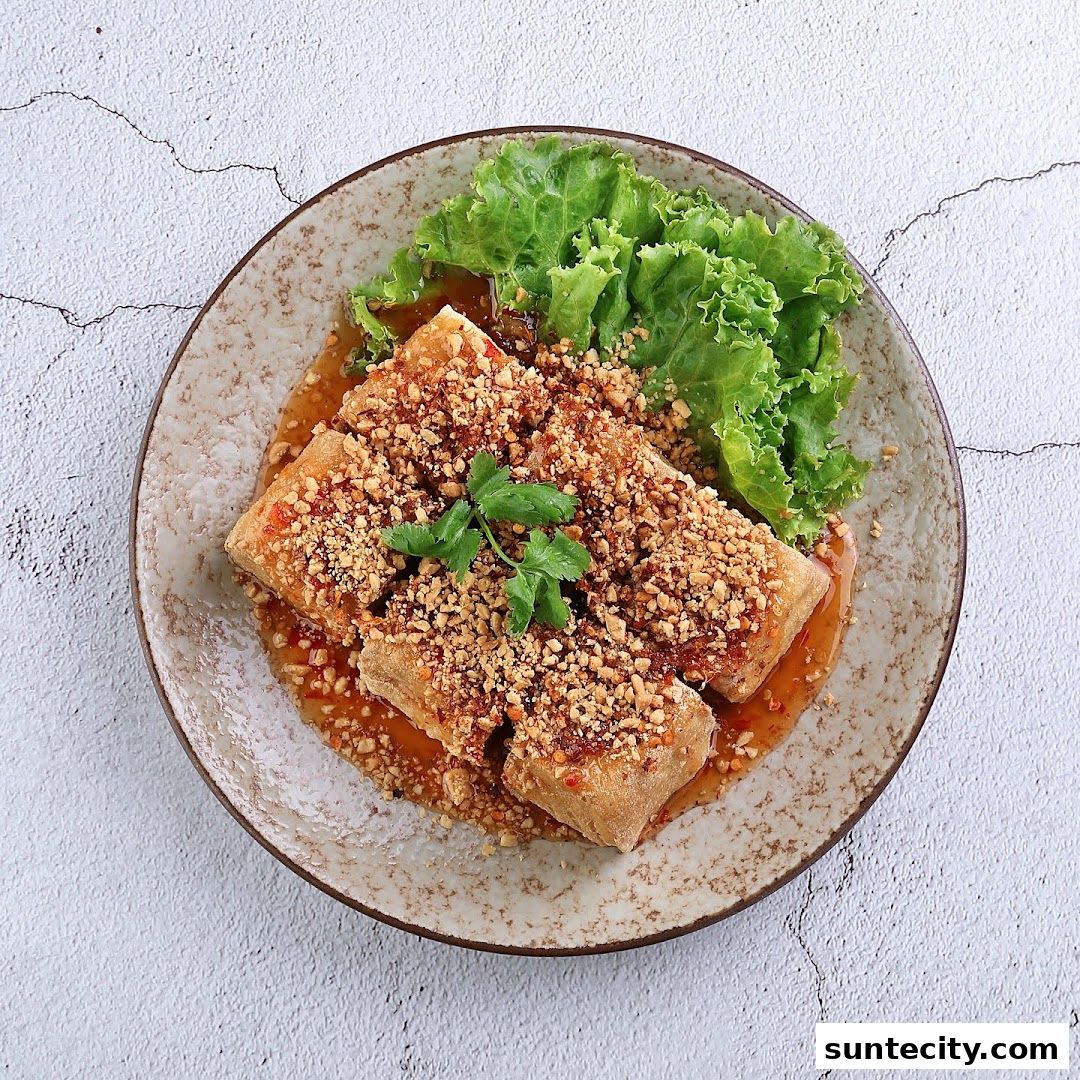 A plate of crispy fried tofu topped with crushed peanuts and chili sauce, served with lettuce.