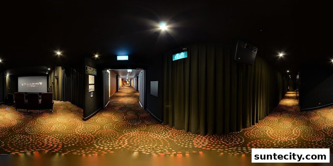 A cinema hallway with patterned carpet, dark walls, and exit signs.