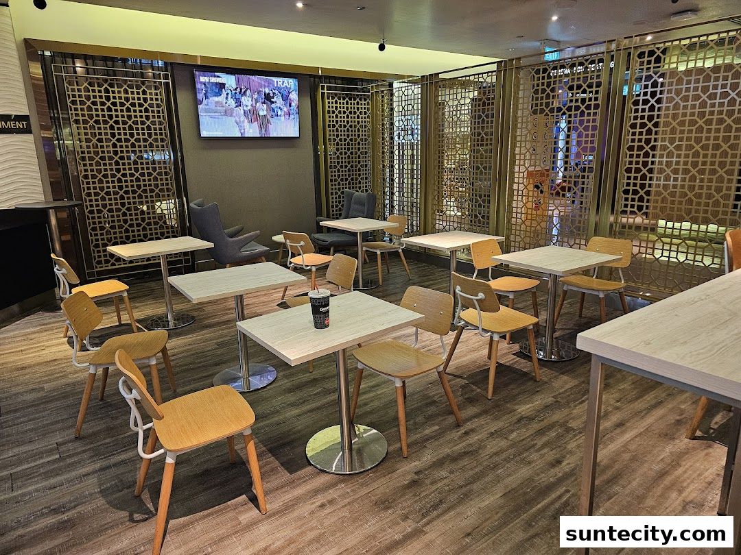A seating area with tables and chairs, featuring decorative screens and a TV screen.
