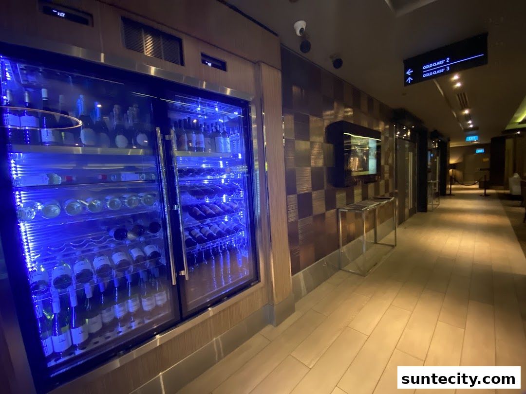 A well-lit hallway with a refrigerated wine display and directional signage.