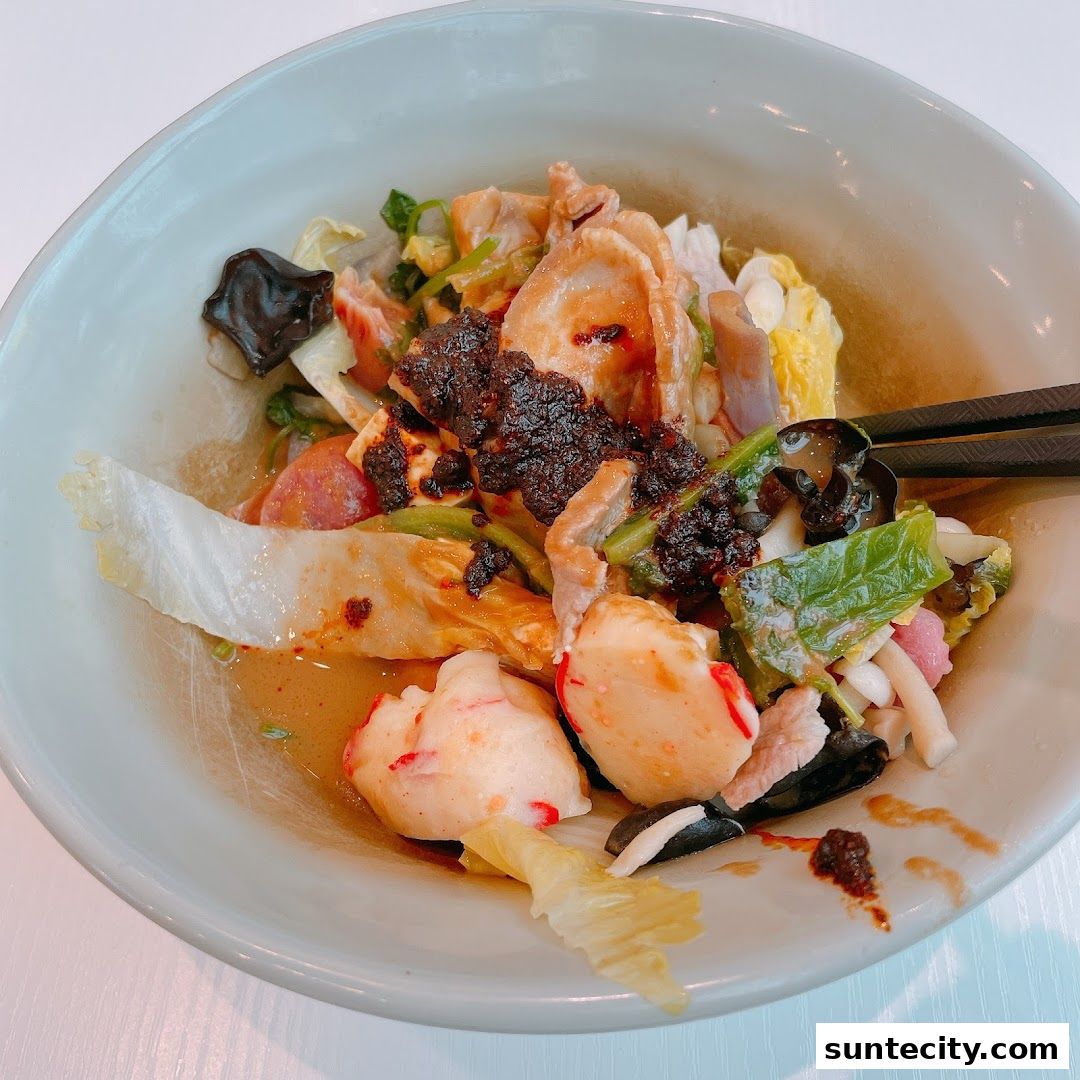 A close-up of a bowl of Mala Tang with various ingredients and chopsticks.