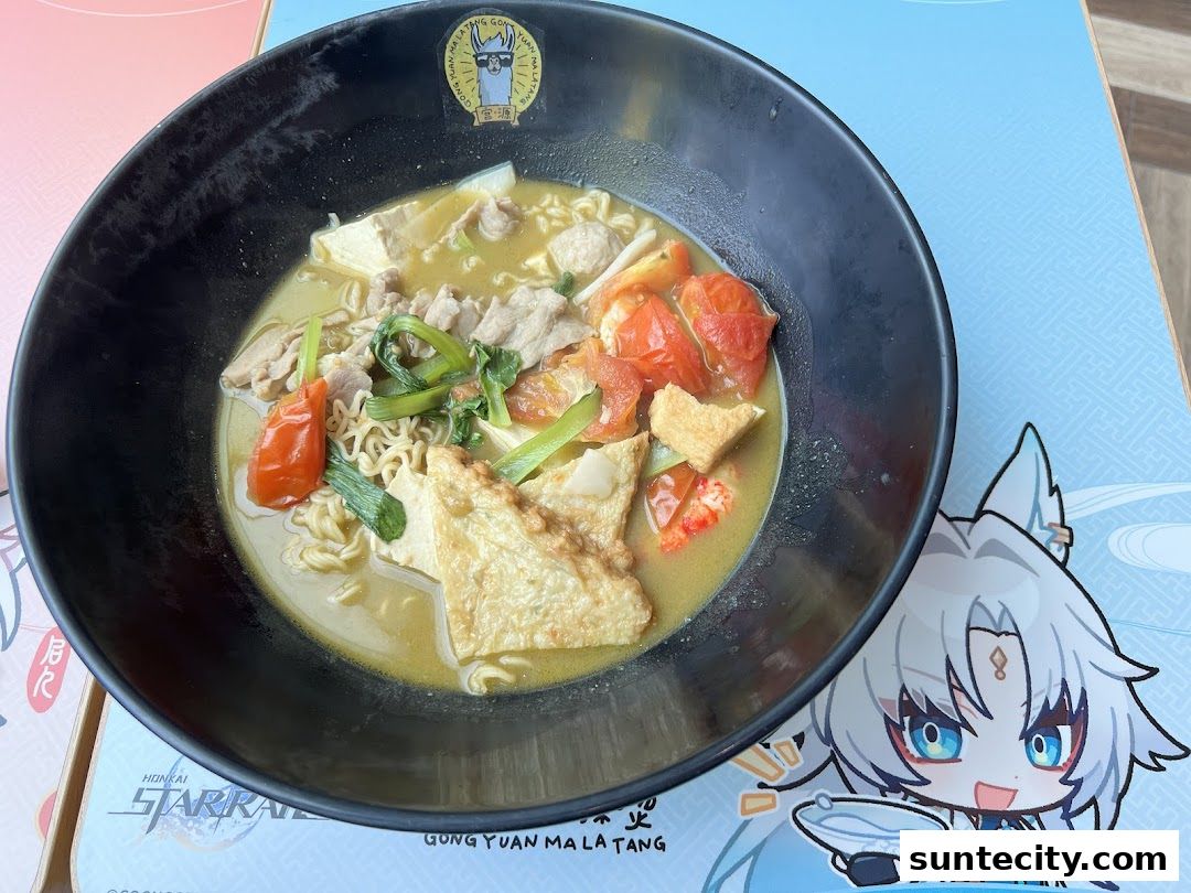A bowl of Mala Tang with noodles, meat, tofu, and tomatoes, next to a character sticker.