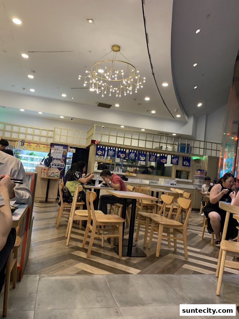 Diners enjoy meals at tables inside a brightly lit restaurant with modern decor.