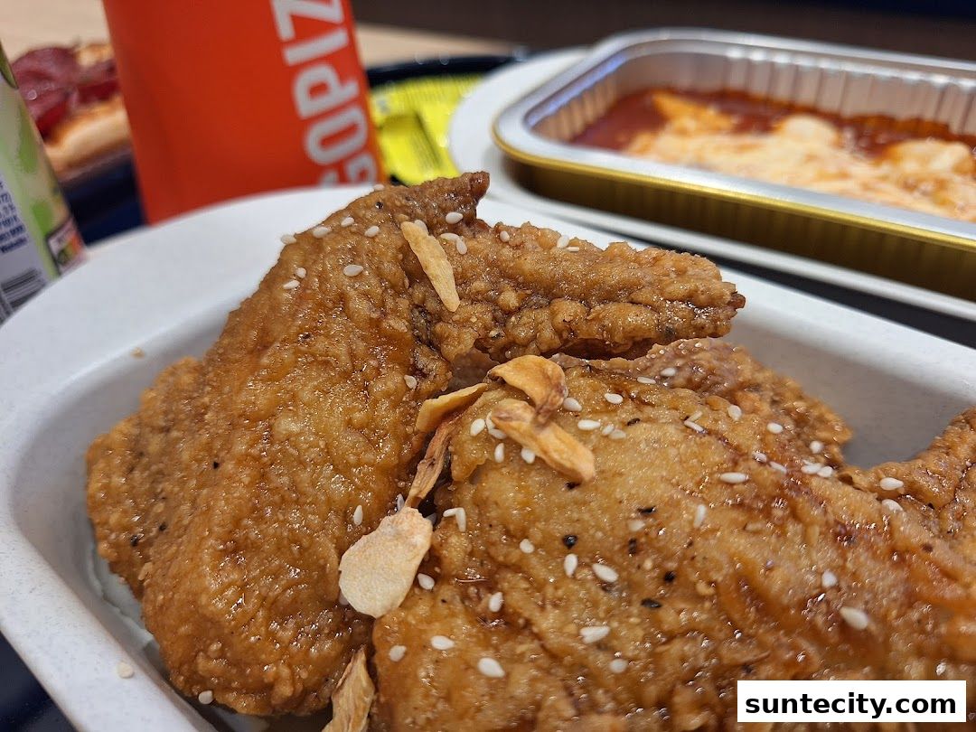 Close-up of crispy fried chicken wings with sesame seeds and garlic chips.