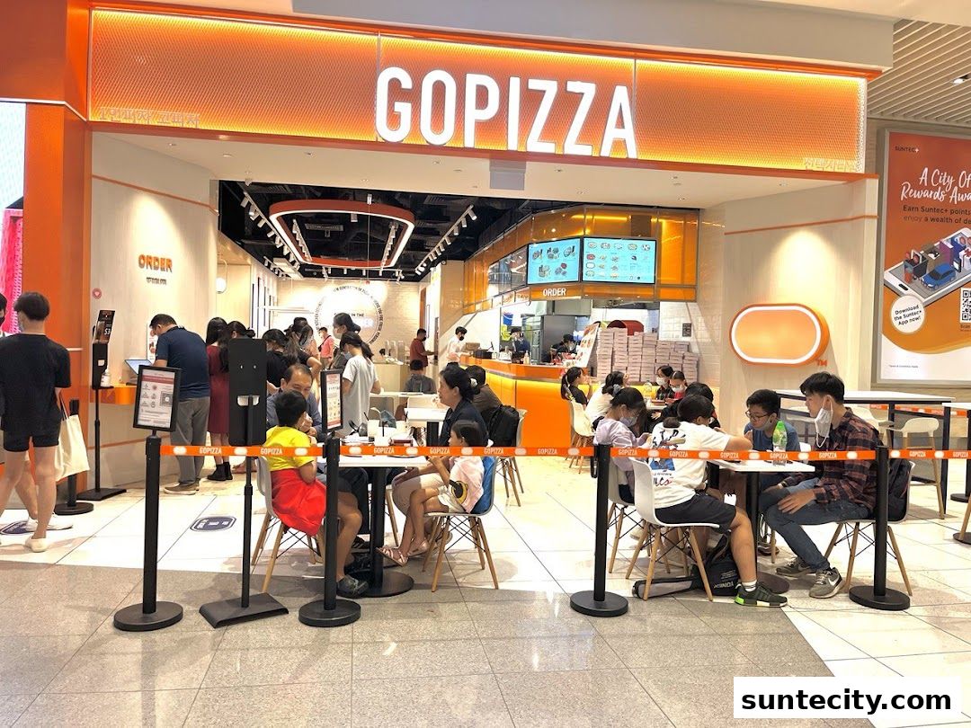 People dining and queuing at GOPIZZA, a pizza restaurant with bright orange signage.