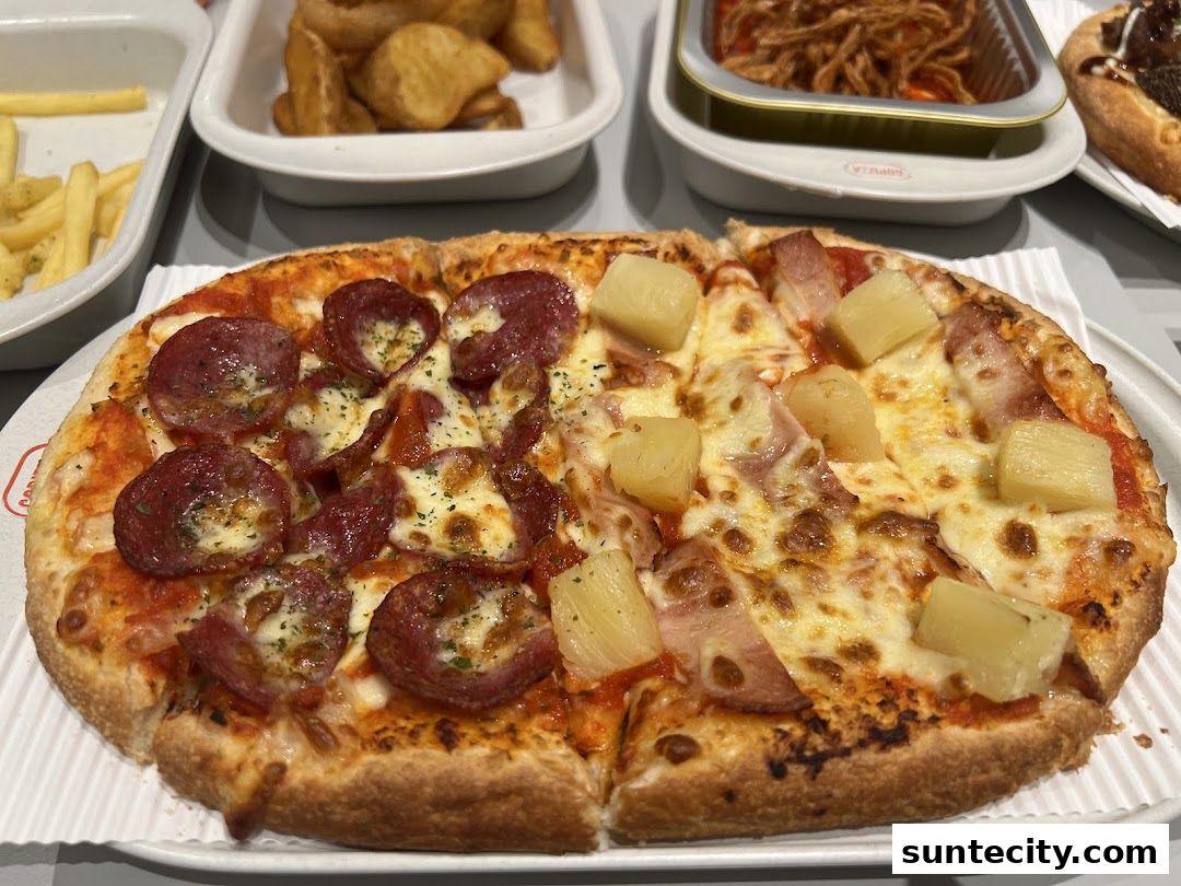 A delicious half pepperoni and half pineapple pizza with sides of fries and onion rings.