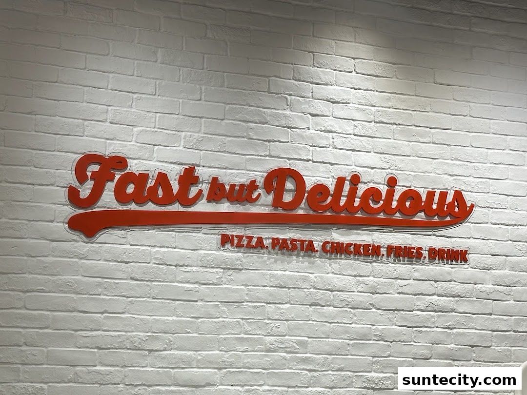 A red neon sign on a white brick wall reads 'Fast but Delicious' and lists menu items.