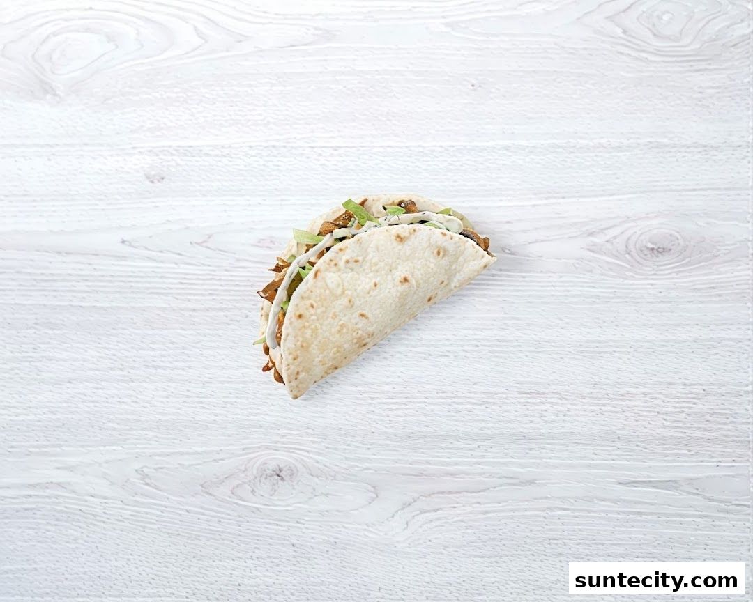 A delicious taco filled with meat and vegetables on a white wooden background.