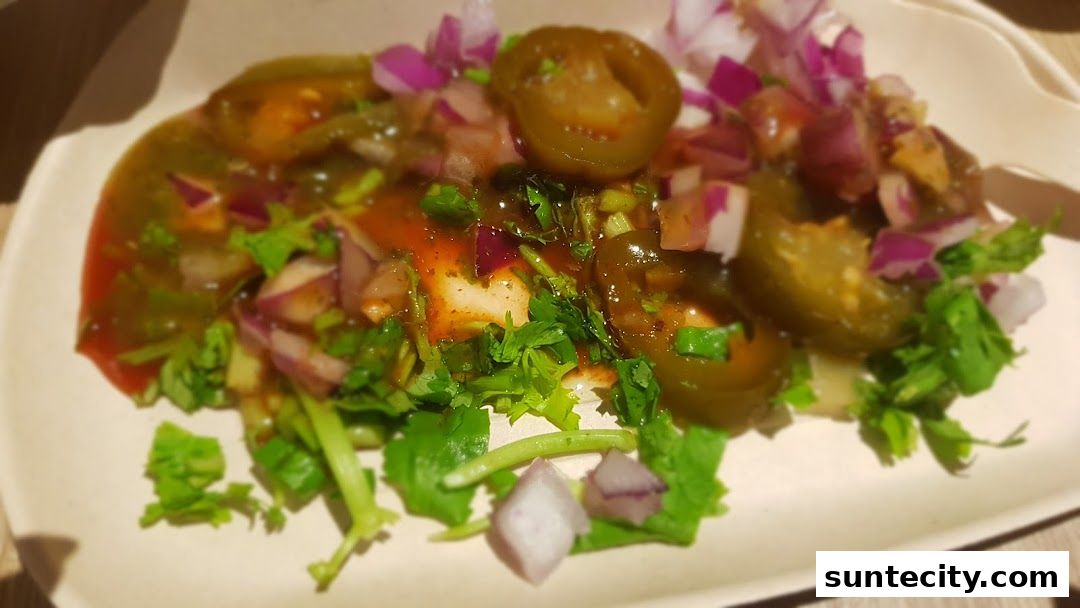 A close-up of a dish with jalapeños, onions, cilantro, and sauce on a white plate.