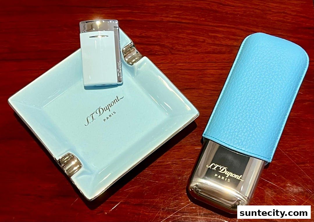 A light blue S.T. Dupont lighter and cigar case with silver accents on a wooden surface.