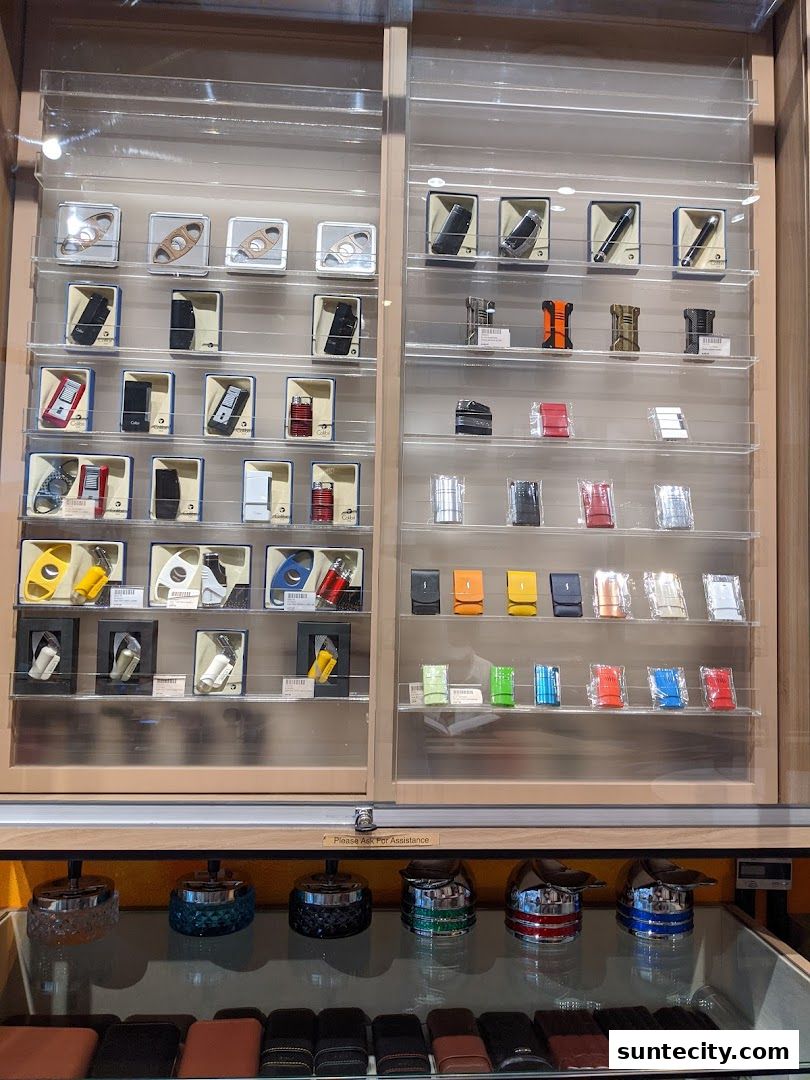 Display cases filled with cigar cutters, lighters, and accessories, with ashtrays and cases below.