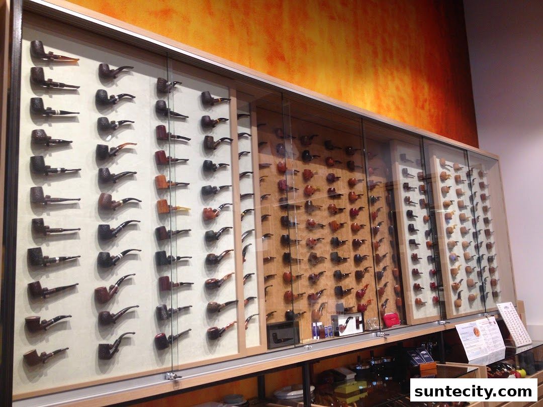A display of numerous smoking pipes in a shop with a vibrant orange and yellow wall.