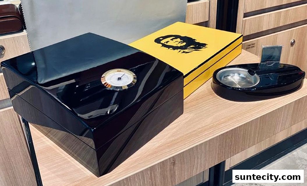 A glossy black humidor with a thermometer sits next to a yellow box with a Che Guevara graphic.