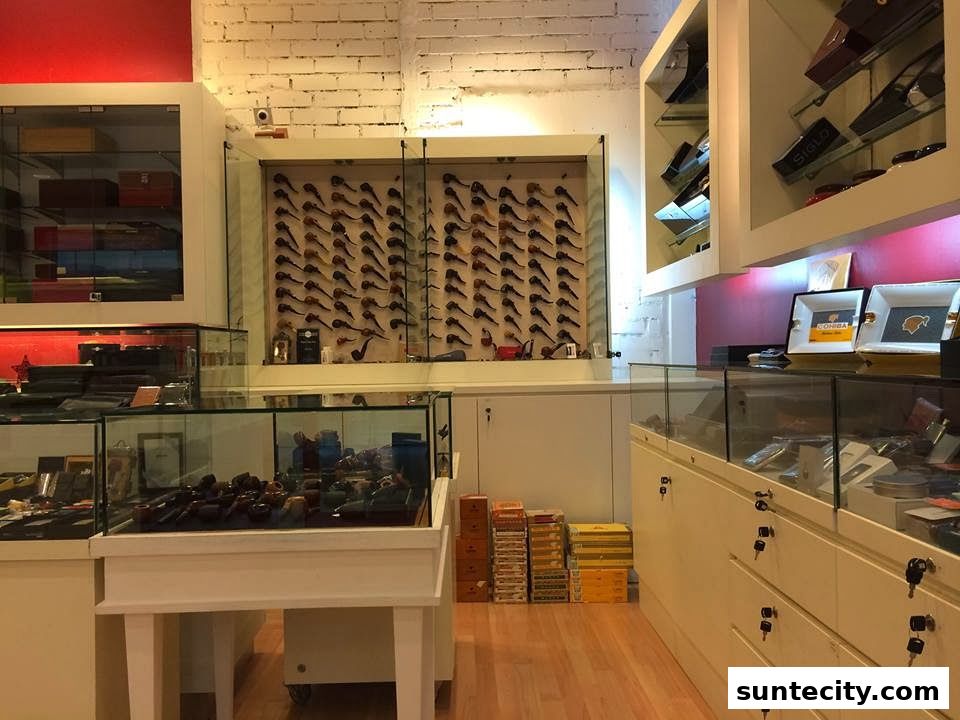 Interior of a shop displaying pipes, cigars, and accessories in glass display cases.
