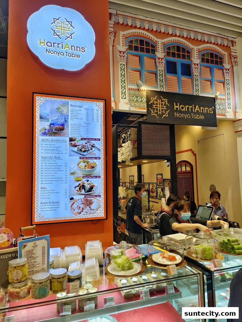 Interior view of HarriAnns Nonya Table with a menu display and staff serving customers.