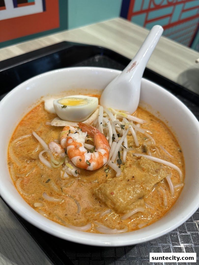 A close-up shot of a delicious bowl of Laksa with shrimp, egg, and bean sprouts.