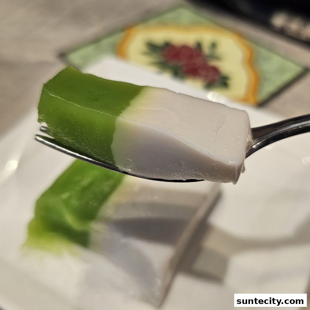 A fork holds a slice of green and white layered dessert, with more dessert in the background.