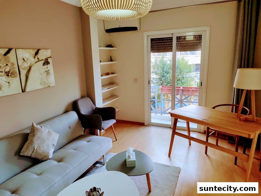 A modern living room with a sofa, armchair, desk, and balcony view.