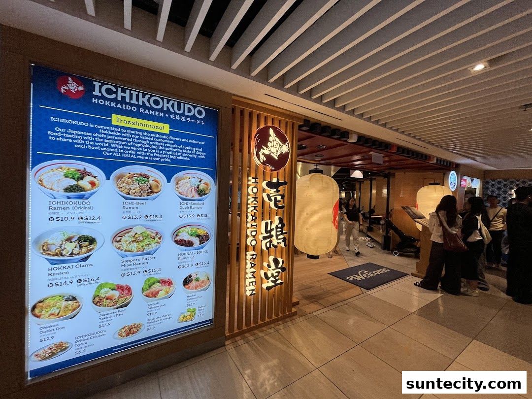 The entrance of Ichikokudo Hokkaido Ramen with a large illuminated menu displaying various ramen dishes.
