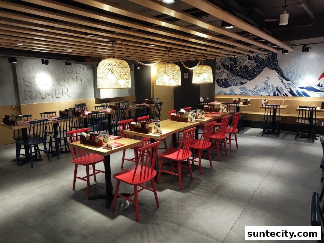 Interior of a ramen restaurant with tables, chairs, and Japanese wave artwork.