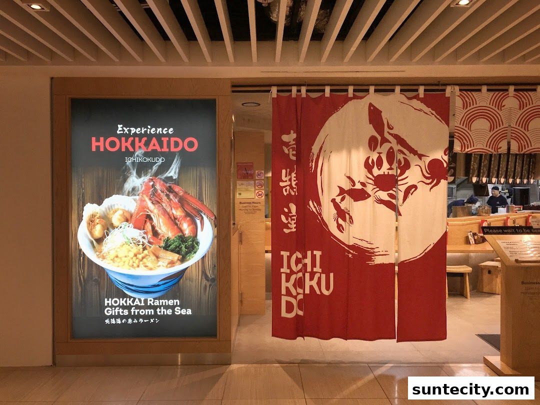 The entrance to Ichikokudo Hokkaido Ramen, featuring a large display of ramen and a red Noren curtain.
