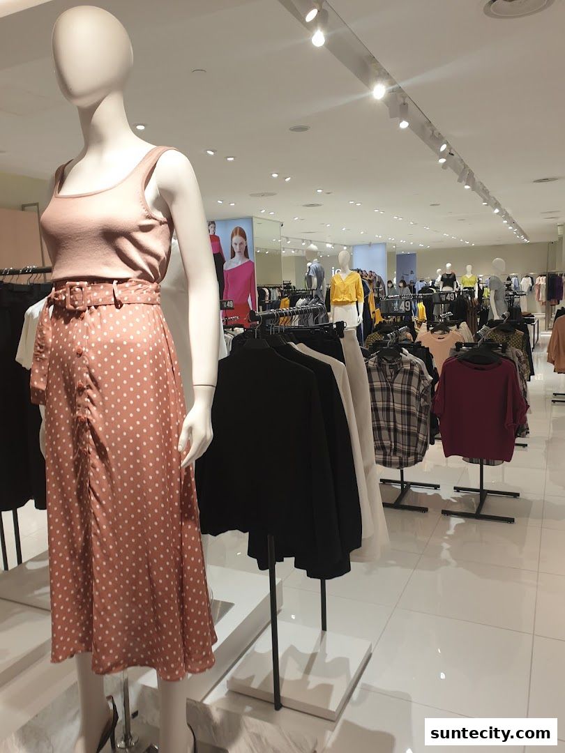 Mannequins and clothing racks display fashionable apparel inside a bright retail store.
